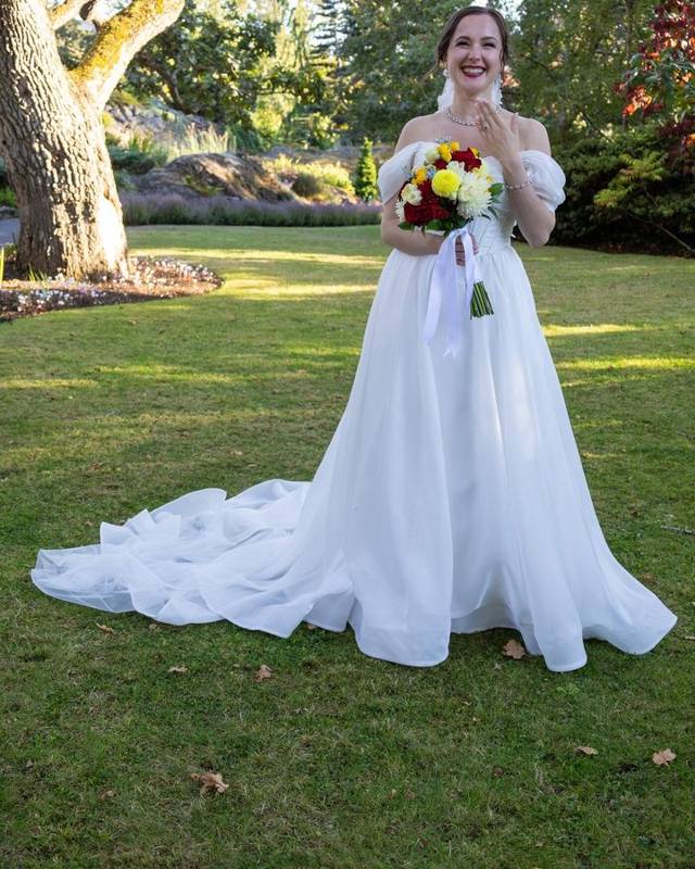 Bride laughing on a sunny lawn holding her bouquet