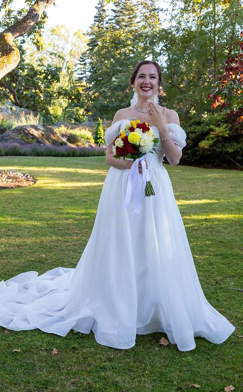 Bride laughing on a sunny lawn holding her bouquet