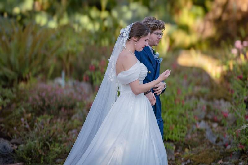 Bride and groom standing close in a sunlit flower garden