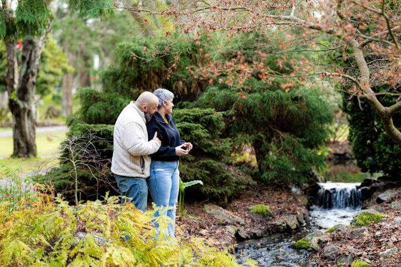 Couple embracing among garden shrubs beside a small waterfall