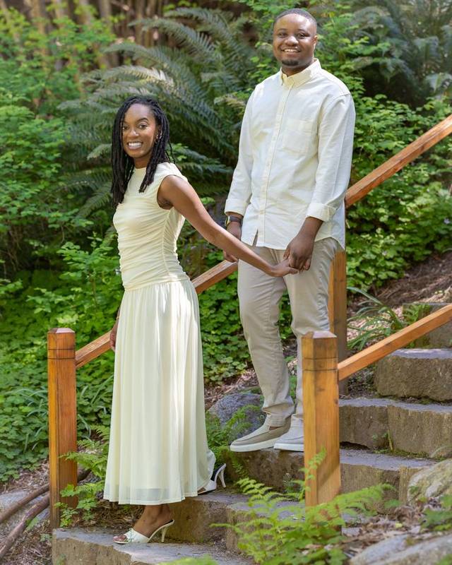 Couple holding hands on wooden garden stairs among ferns