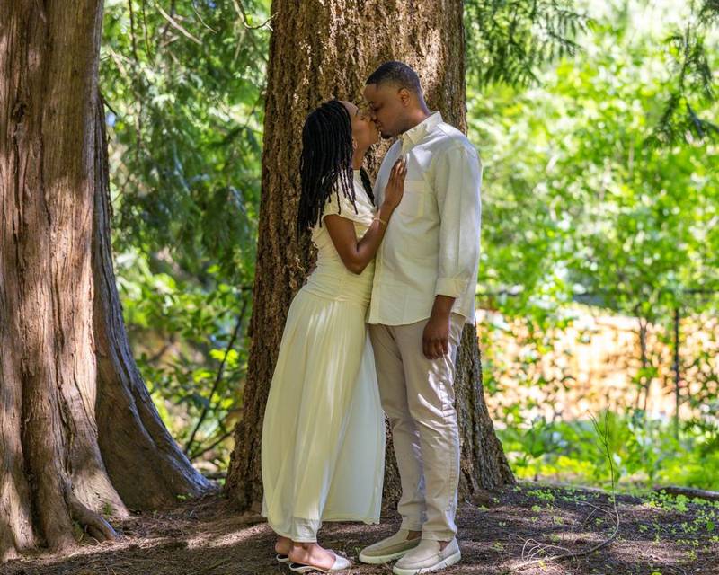 Couple kissing beside a tall cedar tree