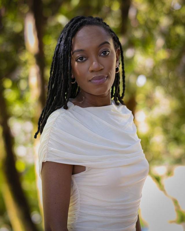 Portrait of a woman in a cream top against soft forest light