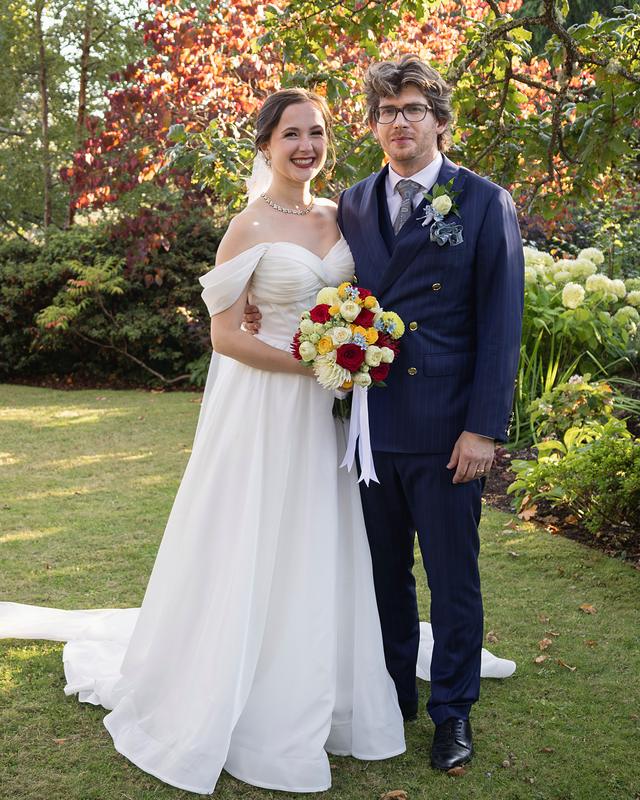 Bride and groom smiling at the camera in an autumn garden